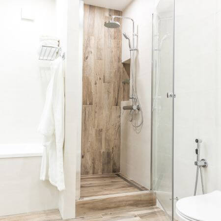 Bathroom-Conversion-4 Modern bathroom showcasing a shower, toilet, and stylish wooden flooring.