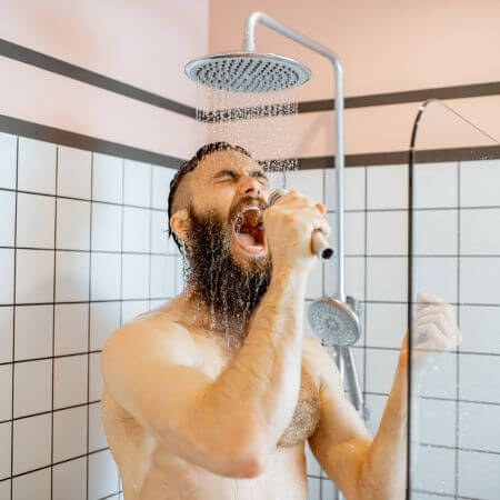 Shower-Remodeling-2 A bearded man in the shower, holding a microphone, smiling as he enjoys his routine.